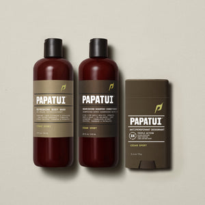 PAPATUI™ Body Care Bundle in Cedar Sport scent, featuring the full set: Refreshing Body Wash 18 fl oz, Nourishing Shampoo + Conditioner 18 fl oz, and Antiperspirant Deodorant 2.6 oz. Products are arranged on a soft beige background, showcasing consistent amber and brown minimalist packaging with bold PAPATUI™ branding.