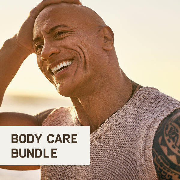 Dwayne "The Rock" Johnson smiling outdoors at sunset running his hand over his bald head. His shoulder tattoo is partially visible, and he is wearing a light-colored sleeveless textured shirt. Text overlay reads “Body Care Bundle.” The golden light highlights his skin tone and joyful expression.
