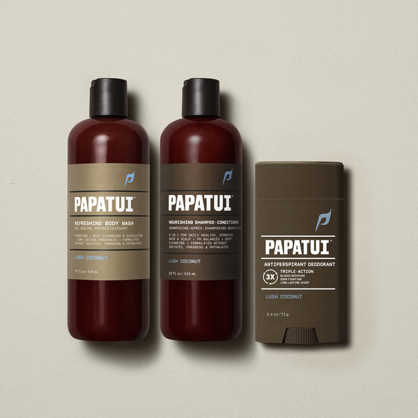 PAPATUI™ Body Care Bundle in Lush Coconut scent, featuring the full set: Refreshing Body Wash 18 fl oz, Nourishing Shampoo + Conditioner 18 fl oz, and Antiperspirant Deodorant 2.6 oz. Products are arranged on a soft beige background, showcasing consistent amber and brown minimalist packaging with bold PAPATUI™ branding.
