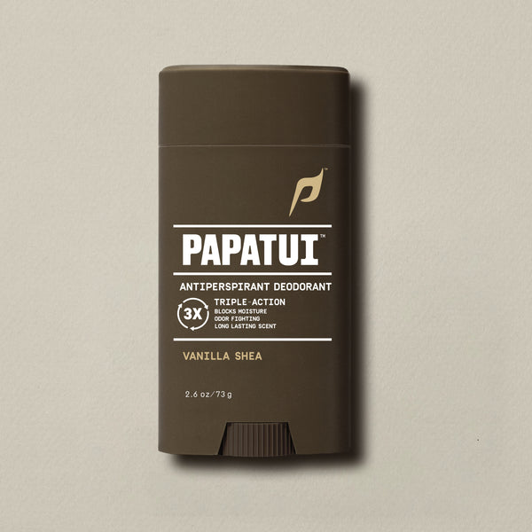 PAPATUI™ Antiperspirant Deodorant 2.6 oz in Vanilla Shea scent. The product is housed in a dark brown stick with a minimalist beige and white label and light blue PAPATUI™ logo. Callouts on the label highlight triple-action benefits: blocks moisture, odor fighting, and long-lasting scent. Positioned against a neutral beige background.