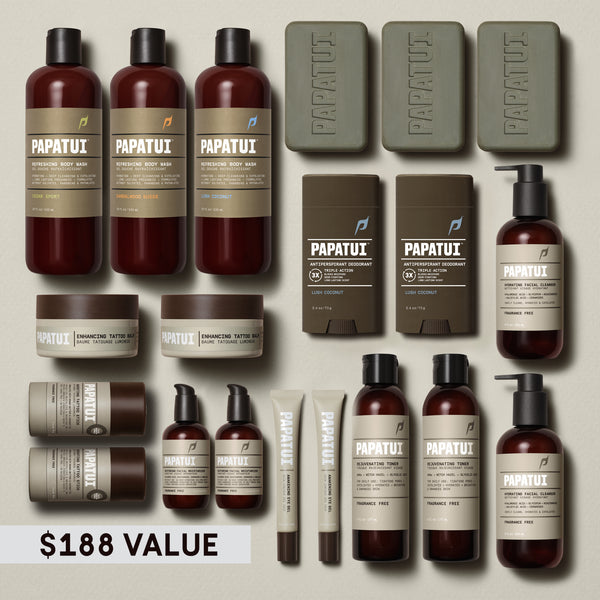Papatui's full line up of products on a plain beige background consisting of 3 body wash, 3 bar soap, 2 deodorant, 2 facial cleanser, 2 facial toner, 2 moisturizer, 2 eye gel,  tattoo stick, and 2 tattoo balm with a brown text reading $188 value.