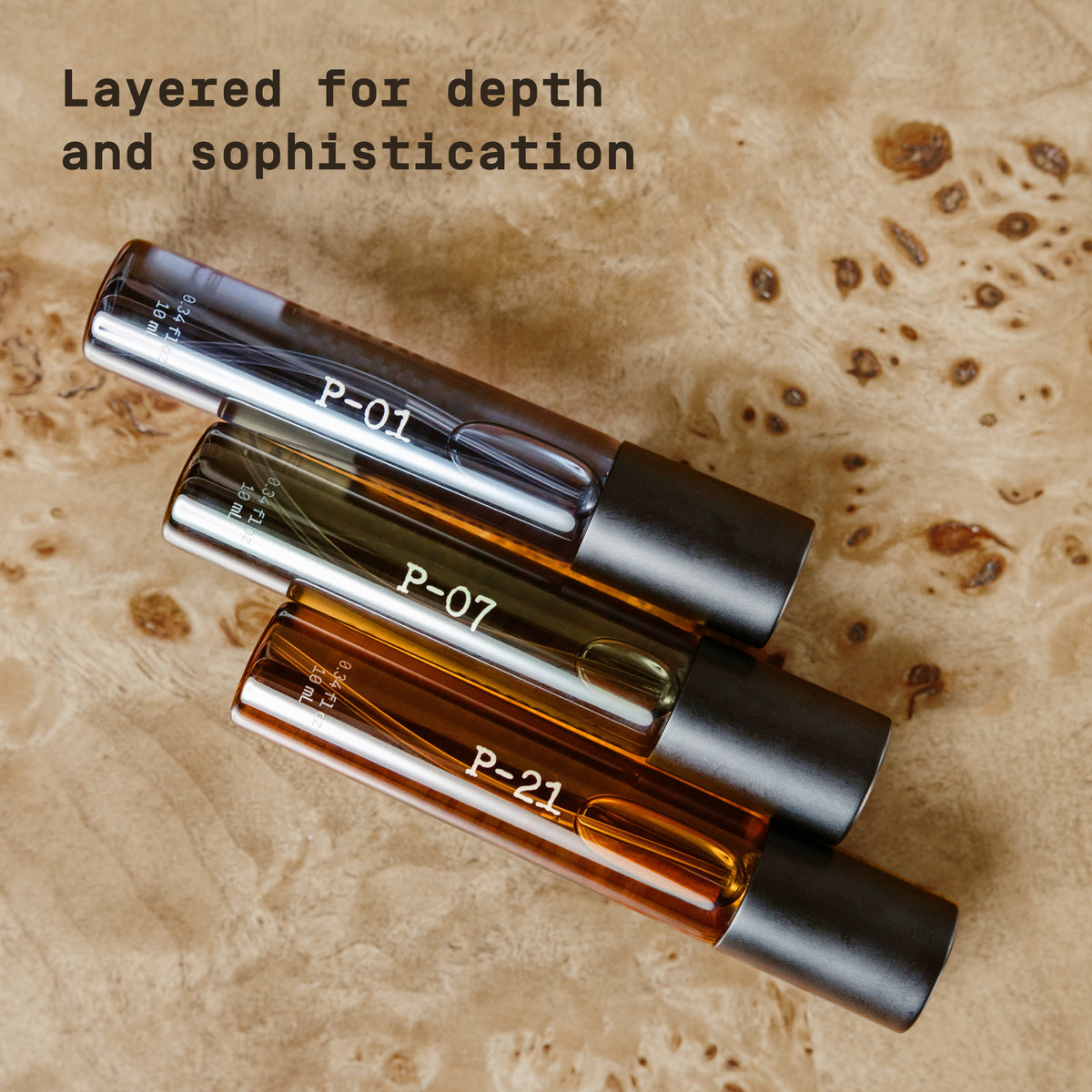 Three PAPATUI Luxury Cologne Discovery Set bottles - P-01 (blue), P-07 (green), P-21 (amber) on a light wooden background with text overlay reading "Layered for depth and sophistication"
