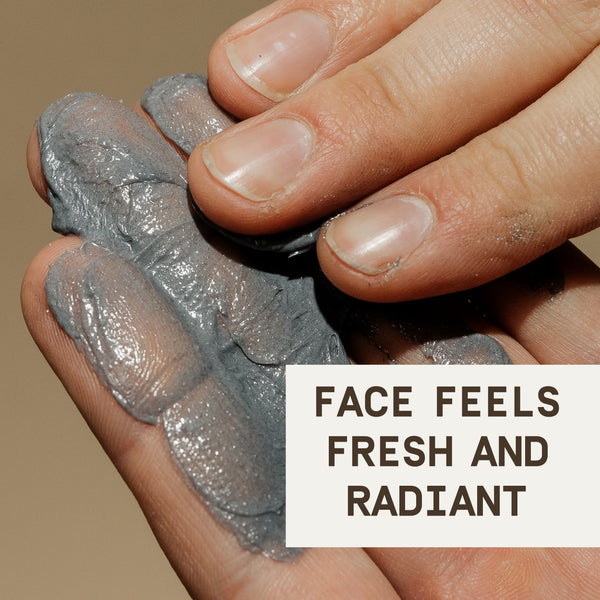 A close-up image showcasing the PAPATUI™ Exfoliating Facial Scrub Unscented 4oz being spread across a hand. The thick, dark gray scrub with a slightly shimmery texture is visible, highlighting its exfoliating properties. A text overlay in bold letters reads, ‘FACE FEELS FRESH AND RADIANT,’ emphasizing the product’s skin-refreshing benefits. The background is neutral, keeping the focus on the texture and application of the scrub.