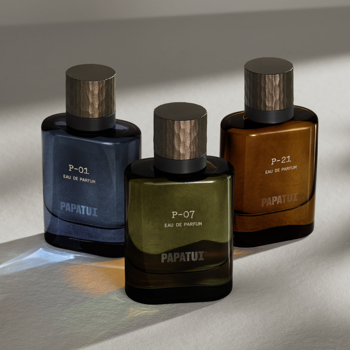 Three PAPATUI Luxury Cologne bottles - P-01 (blue), P-07 (green), P-21 (amber) on a neutral background