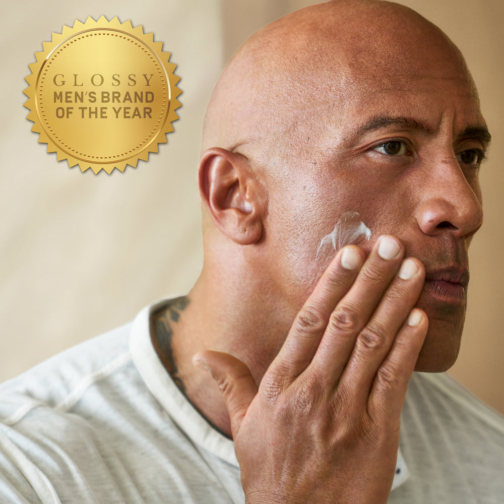 Dwayne "The Rock" Johnson applying PAPATUI Men’s Lightweight Facial Moisturizer with SPF 30 to his face against a neutral background with a gold award badge in the top left corner with text that reads "Glossy Men's Brand of the Year"