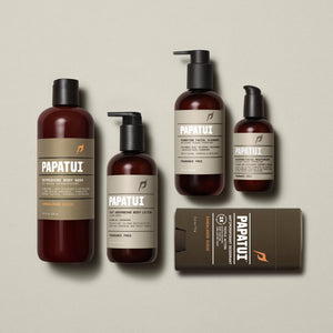 PAPATUI™ Take Better Care Bundle featuring the complete set: Refreshing Body Wash 18 fl oz Sandalwood Suede, Fast Absorbing Body Lotion 11.5 fl oz fragrance-free, Hydrating Facial Cleanser 8 fl oz fragrance-free, Restoring Facial Moisturizer 3.3 fl oz fragrance-free, and Antiperspirant Deodorant 2.6 oz Sandalwood Suede. Products are arranged on a soft beige background with consistent amber and brown minimalist packaging and bold PAPATUI™ branding.