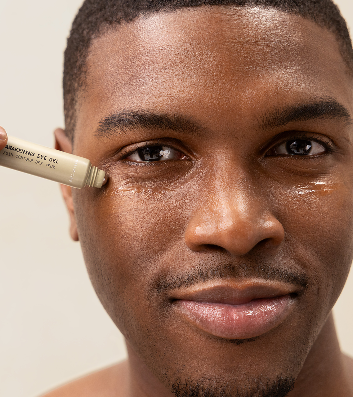 Man applying PAPATUI Rejuvenating eye gel to his under-eye against a neutral background