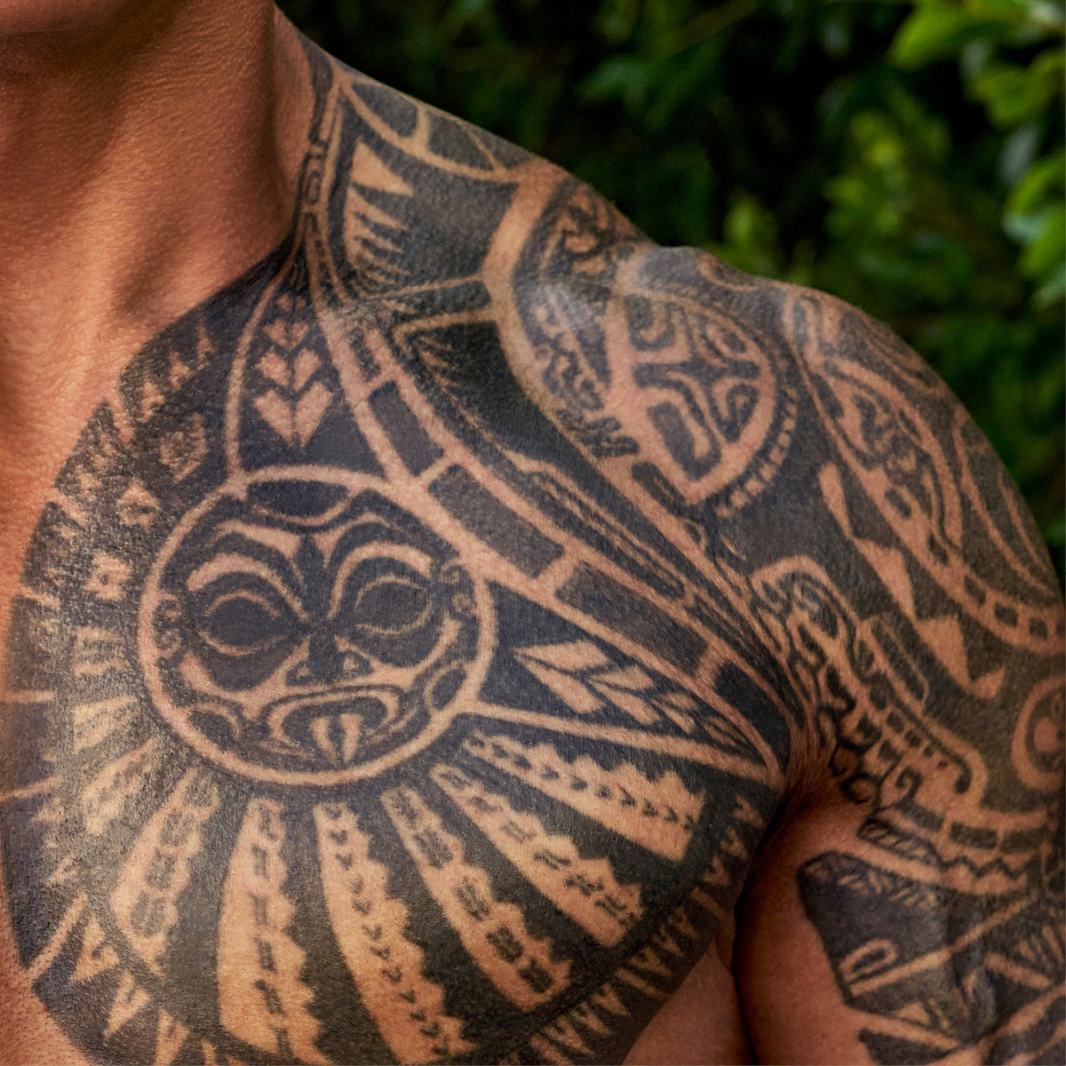 Close-up of a tribal tattoo design on Dwayne "The Rock" Johnson's chest and shoulder against a natural outdoor background.