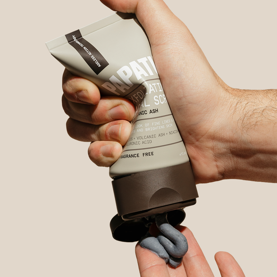 Hand squeezing PAPATUI Exfoliating Facial Scrub into hand against a neutral background