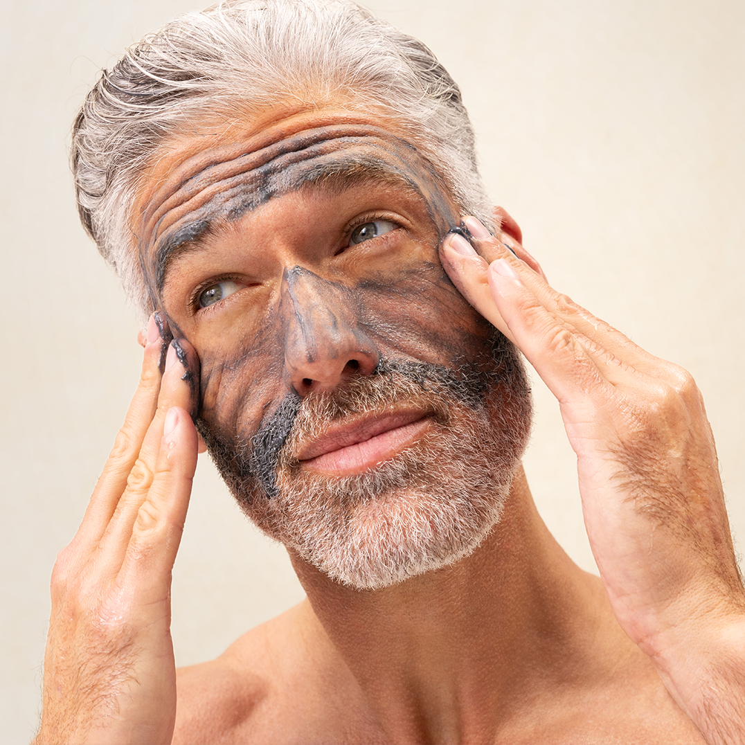 Man applying PAPATUI Exfoliating Facial Scrub to his face against a neutral background