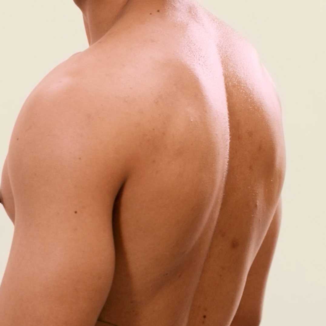 Close-up of a man's shirtless back against a neutral background