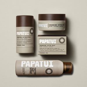 Papatui unscented tattoo stick, tattoo spray and unscented tattoo balm lined up on a plain beige background.