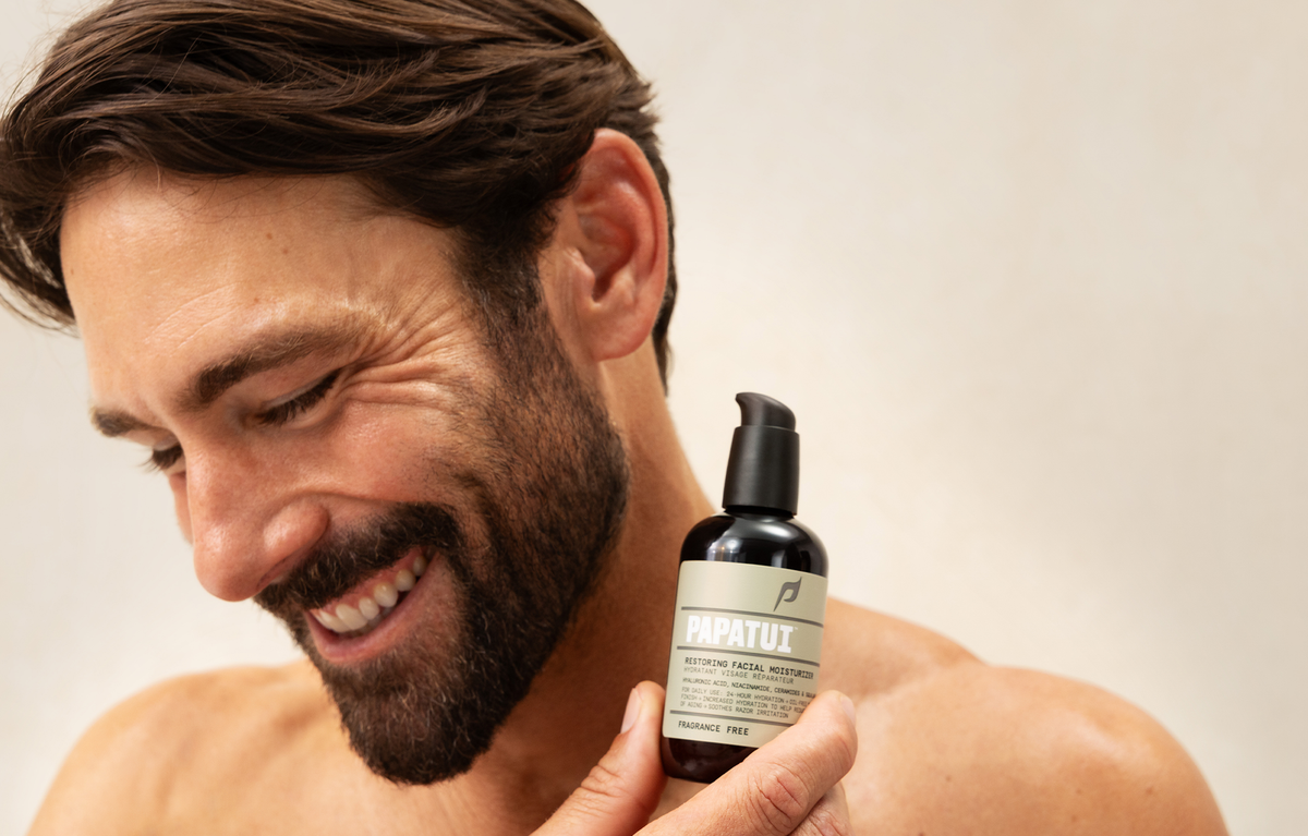 Man holding PAPATUI Restoring Facial Moisturizer against a neutral background
