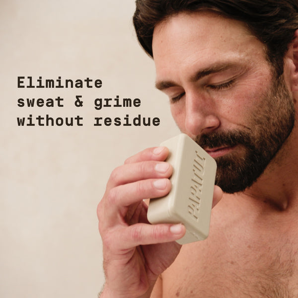 Man holding a Papatui bar of soap with text 'Eliminate sweat & grime without residue' on a beige background