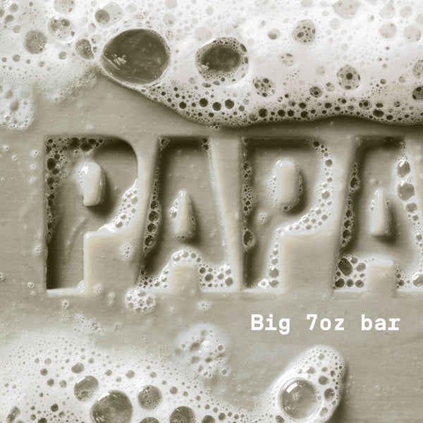 PAPATUI™ Cedar Sport Enriching Big Bar Soap 7oz hardworking and hydrating mens bar soap rich lather. Featuring Vitamin B3, mango butter, avocado oil, and ceramides for deep moisture and cleansing. The image shows a close-up of the embossed "PAPATUI" logo covered in foamy bubbles, emphasizing its luxurious, nourishing formula.