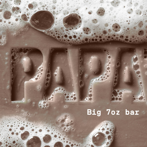 PAPATUI™ Lush Coconut Enriching Big Bar Soap 7oz hardworking and hydrating mens bar soap rich lather. Featuring Vitamin B3, mango butter, avocado oil, and ceramides for deep moisture and cleansing. The image shows a close-up of the embossed "PAPATUI" logo covered in foamy bubbles, emphasizing its luxurious, nourishing formula.