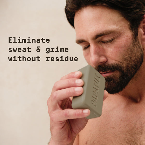 Man holding a Papatui bar of soap with text 'Eliminate sweat & grime without residue' on a beige background.
