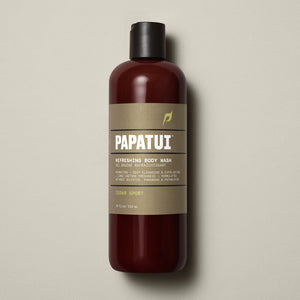 PAPATUI™ Refreshing Body Wash 18 fl oz in Cedar Sport scent. The product is presented in an amber bottle with a beige minimalist label and black flip cap. Key label highlights include hydrating and exfoliating formula with long-lasting freshness. Claims sulfate-free, paraben-free, phthalate-free formulation. Neutral beige background.