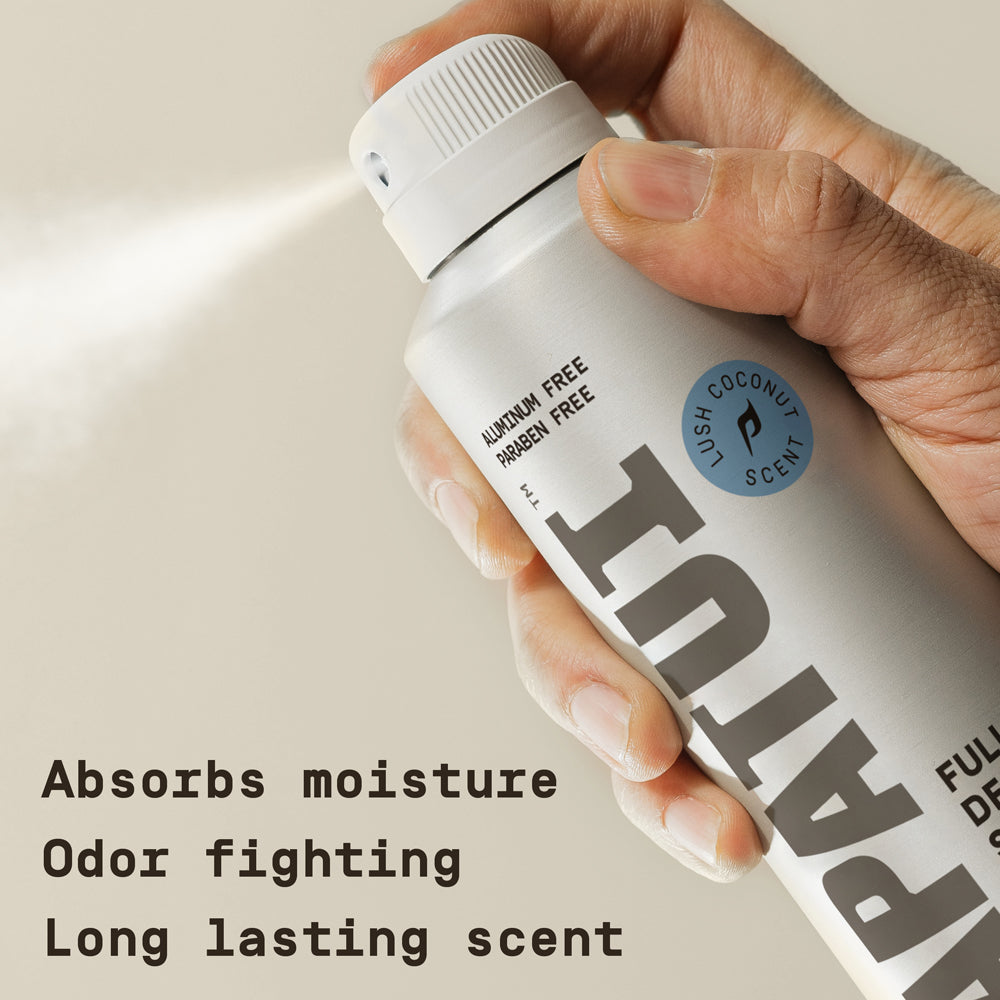 Hand holding a PAPATUI Lush Coconut Full Body Deodorant Spray against a neutral background with text overlay reading "Absorbs moisture Odor fighting Long lasting scent"
