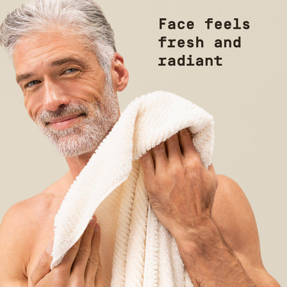 Man holding a towel against a neutral background with text overlay that reads "Face feels fresh and radiant"