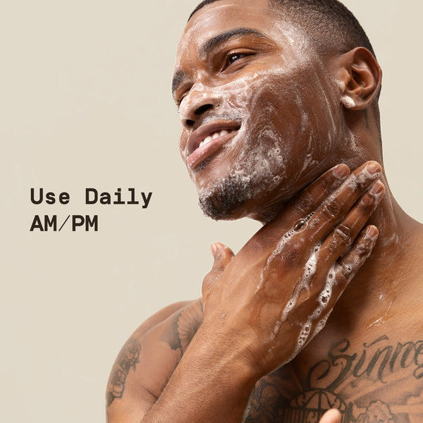 Man applying cleanser to his face with a beige background and text 'Use Daily AM/PM'.