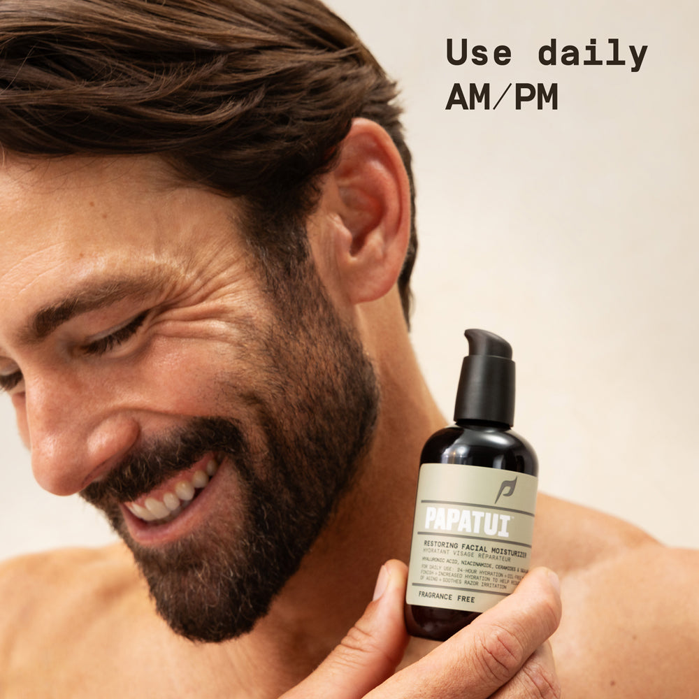 Man holding Papatui Restoring Facial Moisturizer against a neutral background with text overlay that reads "Use daily AM/PM"