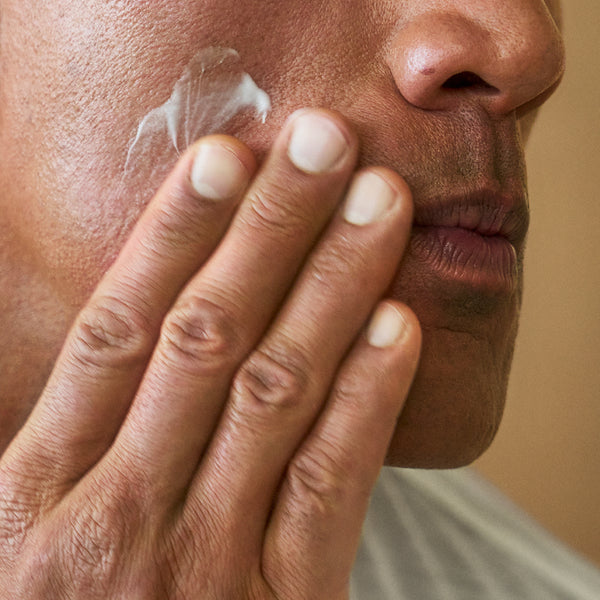 A close-up image of Dwayne Johnson applying PAPATUI™ Unscented Restoring Facial Moisturizer 3.3 oz to his cheek. 