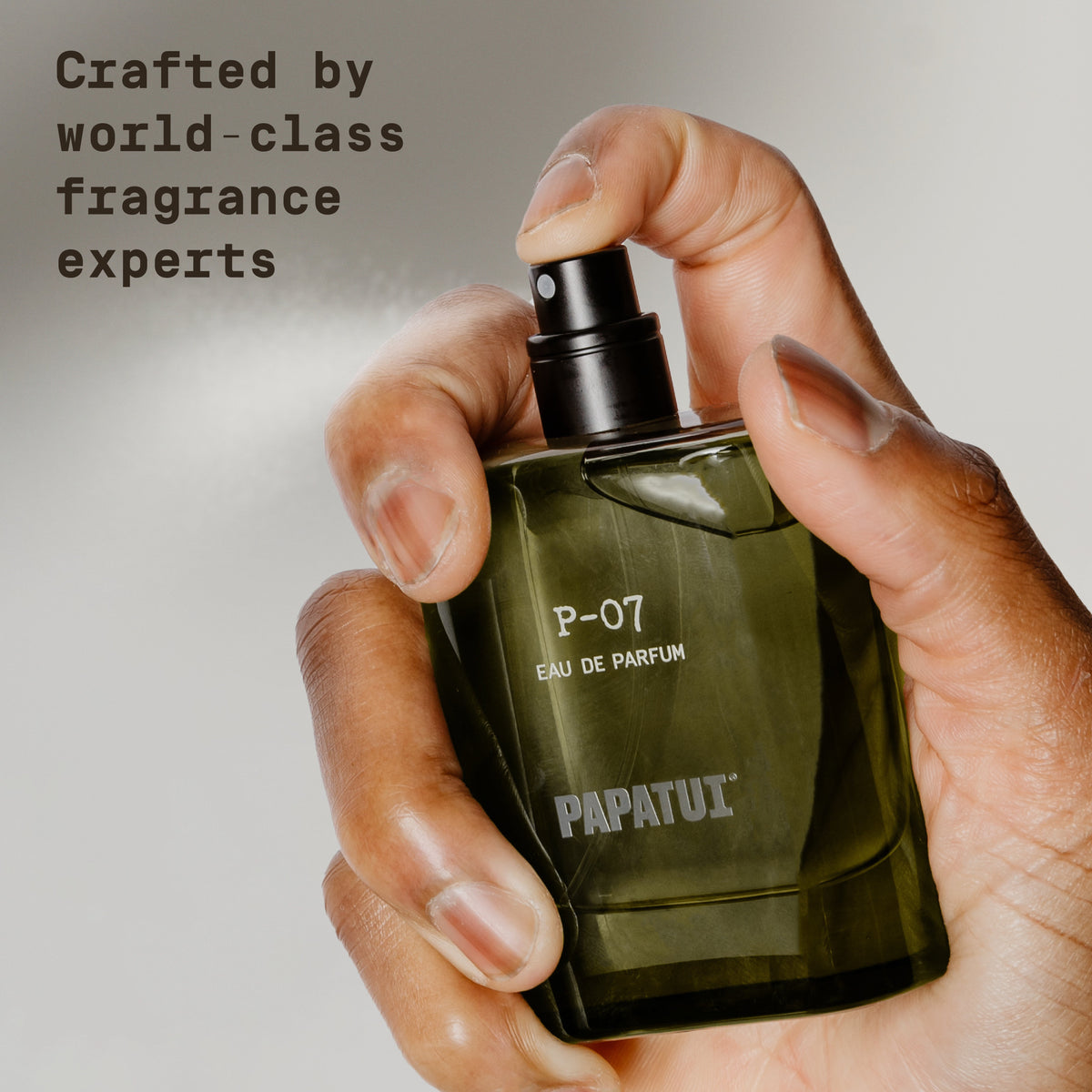 Hand holding a green cologne bottle labeled 'P-07 Eau de Parfum' by 'PAPATUI' on a neutral background with text overlay that reads "Crafted by world-class fragrance experts"