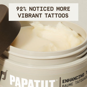 Open jar of PAPATUI™ Enhancing Tattoo Balm 2oz, revealing its smooth, creamy texture. The beige container with a brown lid is designed for nourishing and revitalizing tattooed skin. A bold text overlay states, '92% noticed more vibrant tattoos,' emphasizing user-reported benefits. The product label, partially visible, features the PAPATUI™ branding and product name. The close-up shot highlights the balm’s rich, hydrating formula, which enhances tattoo vibrancy and skin health.