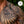 Close-up of Dwayne Johnson’s chest and shoulder tribal tattoo appears vibrant and well-defined, highlighting deep blacks and sharp details. The background features lush green foliage, adding a natural contrast to the tattoo. A circular badge in the top right corner reads 'Cleaner Performance,' reinforcing the effectiveness of PAPATUI™ Enhancing Tattoo Balm 2oz in maintaining tattoo vibrancy and clarity.