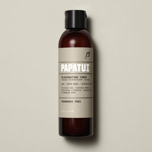 A sleek amber bottle of PAPATUI™ Unscented Rejuvenating Toner 6oz standing upright against a neutral beige background. The label features bold white branding with key product benefits, including hyaluronic acid, niacinamide, ceramides, and squalane for 24-hour hydration, an oil-free matte finish, and soothing razor irritation. The design highlights its fragrance-free formula, making it ideal for daily use and sensitive skin. The aesthetic is minimalist, modern, and premium front of pack.