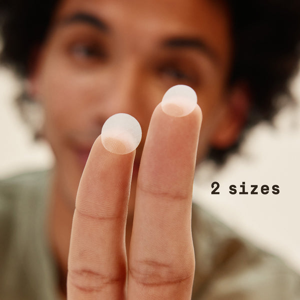 Close-up of a person's hand holding two small white objects with text '2 sizes' of the PAPATUI Pimple patches for men on a blurred background.