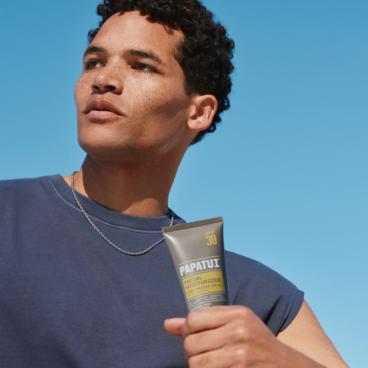 Man holding PAPATUI Facial Moisturizer with SPF against a blue background