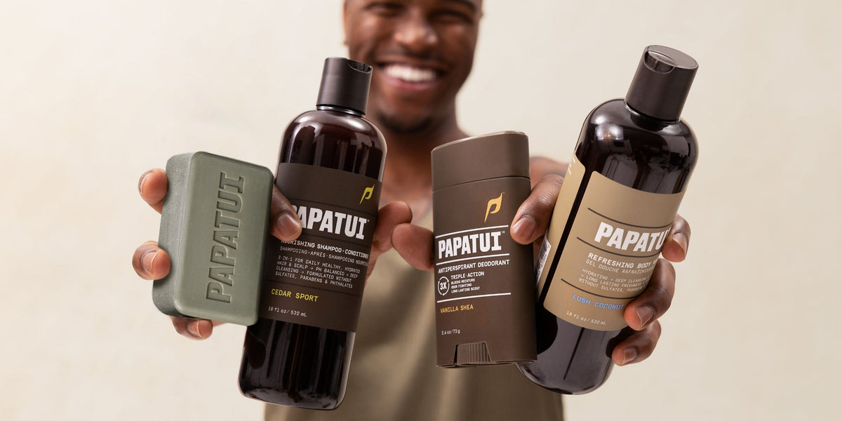 Man holding up assorted PAPATUI products against a neutral, blurred background