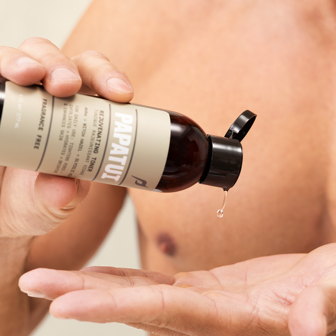 Close-up of man pouring PAPATUI Rejuvenating Toner into his hand