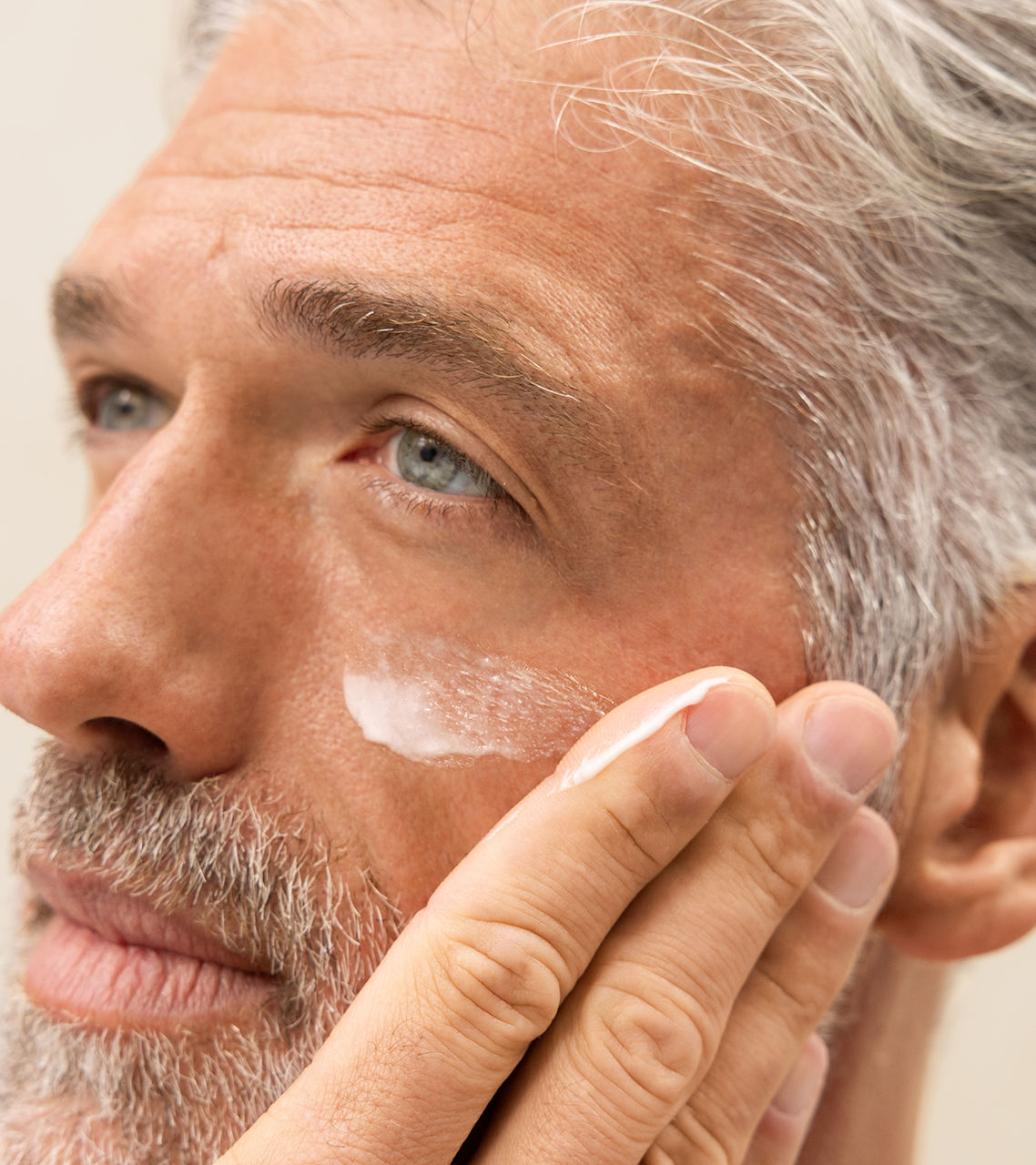 Close-up of man applying white cream to his face