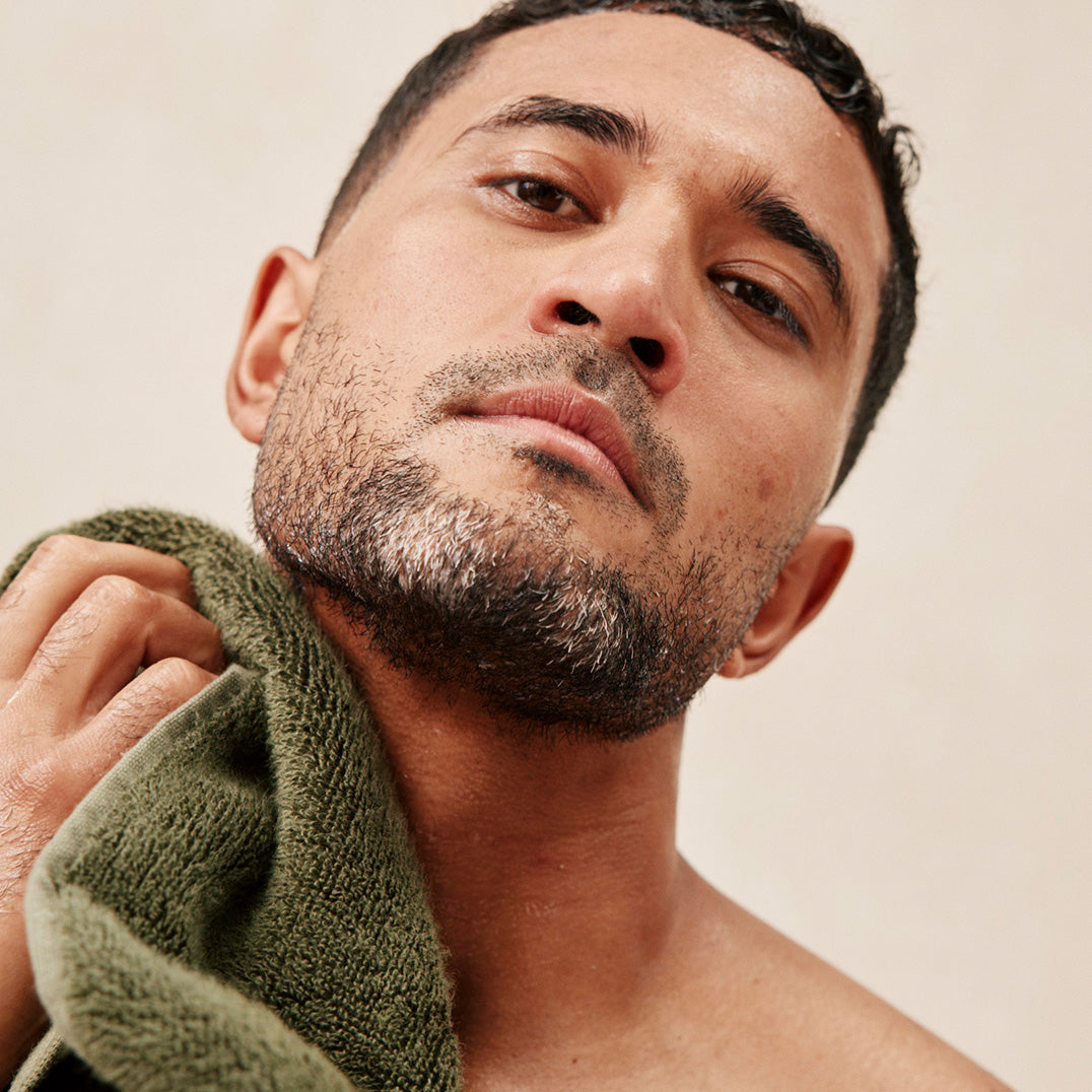 Man with a towel around his neck against a neutral background