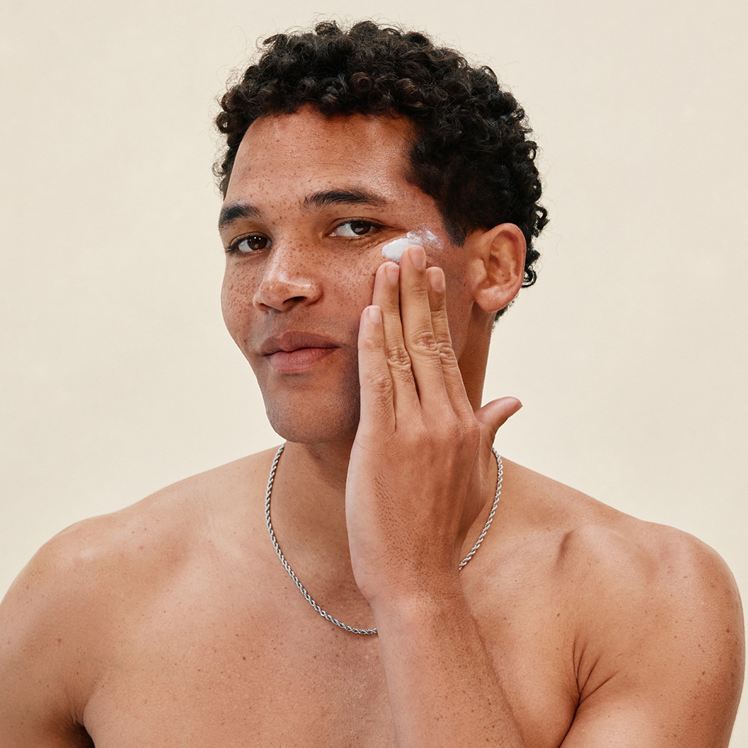 Man applying PAPATUI Restoring Moisturizer to cheek against a neutral background