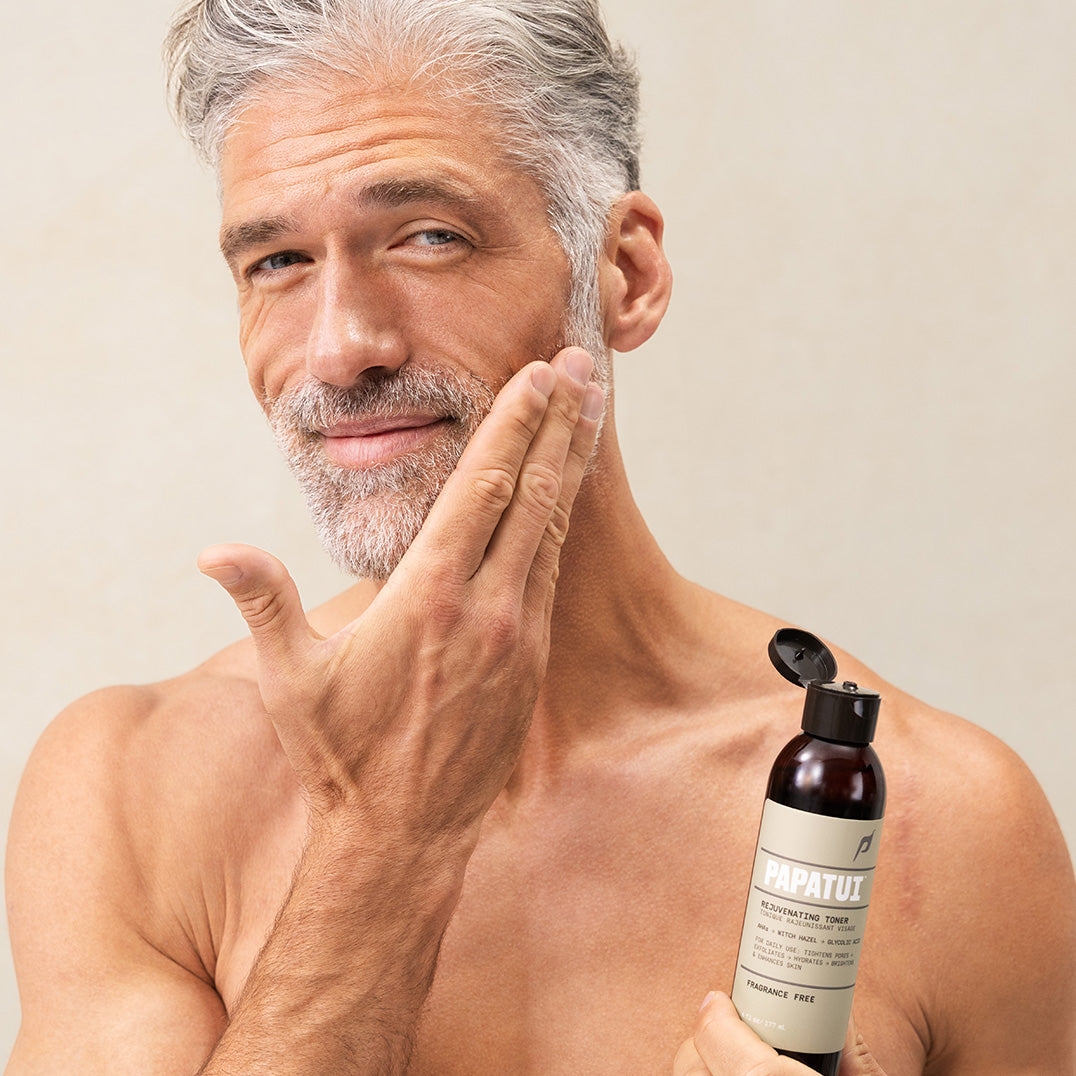 Man applying PAPATUI Rejuvenating Toner to his face against a neutral background
