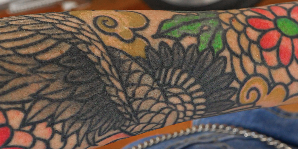 Close-up of a tattooed arm with detailed floral and leaf designs.