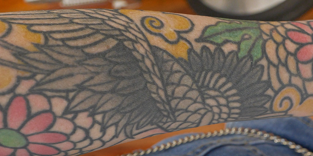 Close-up of a tattoo on a person's arm with floral and leaf designs.