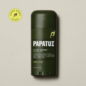 A dark brown stick of PAPATUI 48-Hour Antiperspirant Deodorant in Cedar Sport scent, positioned on a beige background with small dark twigs to the side. The product features orange and white text on the label, promising 48-hour sweat and odor protection, invisibility on clothes, and long-lasting freshness. The deodorant's size is indicated as 2.6 ounces or 73 grams.