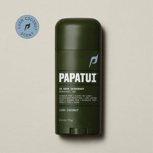 A dark brown stick of PAPATUI 48-Hour Antiperspirant Deodorant in Lush Coconut scent, positioned on a beige background with small dark twigs to the side. The product features orange and white text on the label, promising 48-hour sweat and odor protection, invisibility on clothes, and long-lasting freshness. The deodorant's size is indicated as 2.6 ounces or 73 grams.
