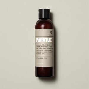 A bottle of PAPATUI Rejuvenating Toner placed on a beige surface. The dark brown bottle has a black cap and features a label in a muted green tone. The toner is described as suitable for daily use to tighten pores, exfoliate, hydrate, brighten, and enhance skin, and is noted as fragrance-free. The volume is listed as 6 fl oz or 177 ml.