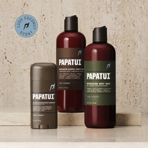 A PAPATUI men's personal care bundle displayed on a marble surface. The set includes a 48-Hour Antiperspirant Deodorant in Lush Coconut scent in a brown stick form, a Nourishing Shampoo-Conditioner, and a Refreshing Body Wash, both in Lush Coconut scent, housed in translucent brown bottles with black caps and green labels detailing their benefits.