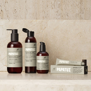 A complete PAPATUI men's face care set arranged on a marble countertop. The set includes a Hydrating Facial Cleanser, Rejuvenating Toner, Restoring Facial Moisturizer, and an Awakening Eye Gel, all in uniform brown bottles with green labels.