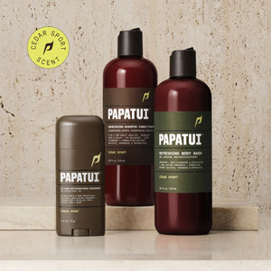 A PAPATUI men's personal care bundle displayed on a marble surface. The set includes a 48-Hour Antiperspirant Deodorant in Cedar Sport scent in a brown stick form, a Nourishing Shampoo-Conditioner, and a Refreshing Body Wash, both in Cedar Sport scent, housed in translucent brown bottles with black caps and green labels detailing their benefits.